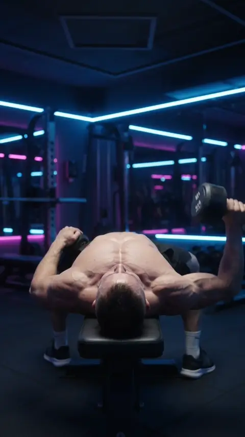 A one-arm dumbbell flye being performed in a gym