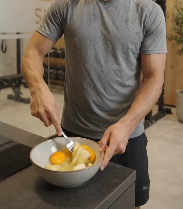Eggs and banana being mixed in a bowl